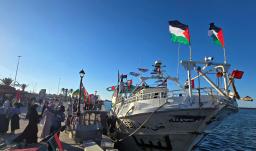 Personas posan para una foto frente al barco Omar al-Mukhtar, un barco libio que zarpó el 17 de septiembre para unirse a la Flotilla Global Sumud, en el puerto de Trípoli.