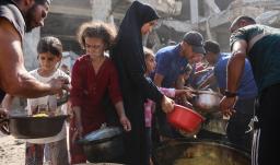Los palestinos desplazados de Gaza se reúnen para recibir raciones de comida frente a la mezquita Imam al Shafi'i, dañada, donde se han refugiado familias, en el barrio de Zeitoun de la ciudad de Gaza.