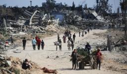Vertriebene Palästinenser gehen an zerstörten Gebäuden vorbei, als sie in ihre Häuser im Gebiet al-Zahra nördlich des Flüchtlingslagers Nuseirat im zentralen Gazastreifen zurückkehren.