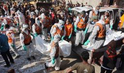 Miembros de Defensa Civil descargan bolsas con los restos mortales de los miembros de la familia Shahebar, que fueron enterrados en tumbas temporales, mientras son trasladados al cementerio Sheikh Shaaban, en la ciudad de Gaza, el 24 de octubre.