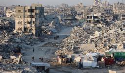 Palestinos caminan entre los escombros de edificios destruidos en el barrio de Sheikh Radwan, en la ciudad de Gaza.