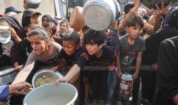 Jóvenes palestinos desplazados esperan con sus recipientes para recibir una ración de comida en el campo de refugiados de Nuseirat, en el centro de la Franja de Gaza, tras hambruna declarada por la ONU en el enclave. 
