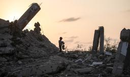 Un joven palestino recoge un trozo de escombro en Nuseirat, durante el genocidio palestino perpetrado por Israel, blanqueado por influencers colombianos