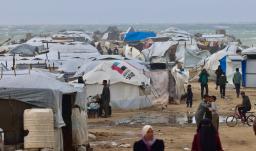 Los desplazados palestinos caminan cerca de tiendas de campaña y refugios improvisados mientras la región sufre las frías condiciones invernales en el campo de refugiados de Al-Mawasi, en el sur de la Franja de Gaza. 