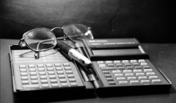 calculadora financiera antigua, gafas y lapicero