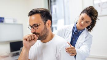 Señor tosiendo muy duro mientras la doctora lo examina