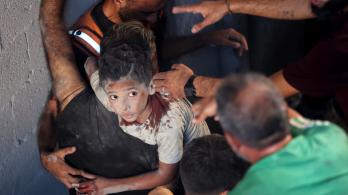 Palestinos transportan a un niño herido en el lugar donde se produjo un ataque israelí que destruyó varios edificios en el barrio de Al-Rimal, en la ciudad de Gaza.