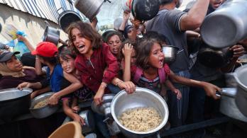 Los palestinos se agolpan para recibir una comida caliente de una cocina benéfica en el campo de refugiados de Nuseirat, en la Franja de Gaza, sitiada por Israel.