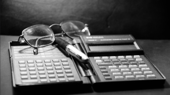 calculadora financiera antigua, gafas y lapicero
