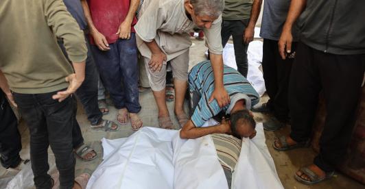 Un palestino llora sobre los cuerpos cubiertos con sábanas de sus familiares, muertos en un ataque israelí contra una panadería improvisada instalada en una tienda de campaña en la calle Al-Nassr, en la ciudad de Gaza.