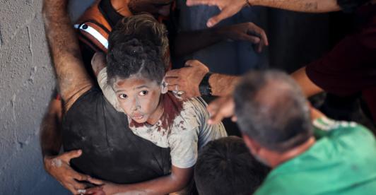 Palestinos transportan a un niño herido en el lugar donde se produjo un ataque israelí que destruyó varios edificios en el barrio de Al-Rimal, en la ciudad de Gaza.