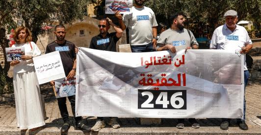 Periodistas árabe-israelíes levantan pancartas y una bandera palestina durante una manifestación en solidaridad con sus compañeros de profesión fallecidos en los ataques israelíes en la Franja de Gaza, en la ciudad norteña de Nazaret, el