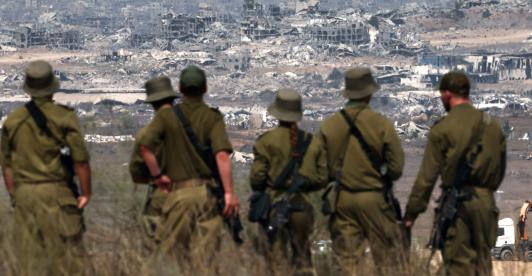 Soldados del ejército israelí observan los edificios destruidos en la Franja de Gaza mientras se encuentran en la frontera con el territorio palestino.