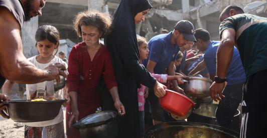Los palestinos desplazados de Gaza se reúnen para recibir raciones de comida frente a la mezquita Imam al Shafi'i, dañada, donde se han refugiado familias, en el barrio de Zeitoun de la ciudad de Gaza.