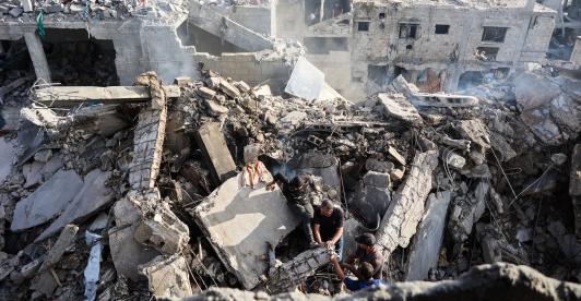 Palestinos intentan recuperar un cadáver de entre los escombros de una casa destruida en un ataque israelí durante la noche, en la ciudad de Gaza.