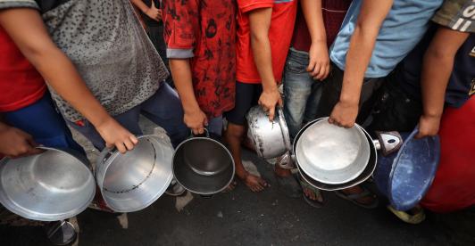 Niños palestinos hacen cola frente a un comedor social en el campo de refugiados de Nuseirat, en el centro de la Franja de Gaza. 