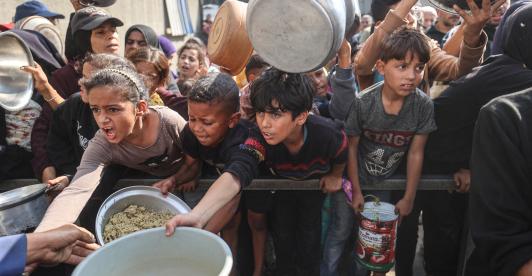 Jóvenes palestinos desplazados esperan con sus recipientes para recibir una ración de comida en el campo de refugiados de Nuseirat, en el centro de la Franja de Gaza, tras hambruna declarada por la ONU en el enclave. 