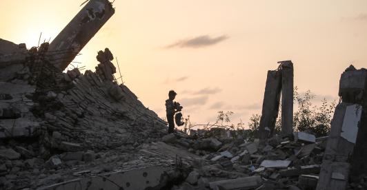 Un joven palestino recoge un trozo de escombro en Nuseirat, durante el genocidio palestino perpetrado por Israel, blanqueado por influencers colombianos