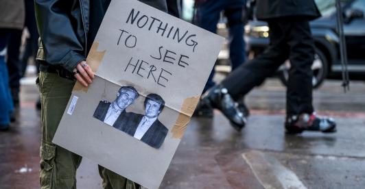 Un manifestante sostiene una pancarta con fotografías de Jeffrey Epstein (izquierda), un acaudalado financiero estadounidense que murió en prisión en 2019 mientras esperaba juicio por tráfico sexual de menores, y del presidente de Estados Unidos, Donald Trump (derecha), durante una manifestación contra el Foro Económico Mundial (FEM) en vísperas de la reunión anual del FEM en Davos.