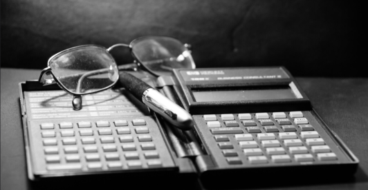 calculadora financiera antigua, gafas y lapicero