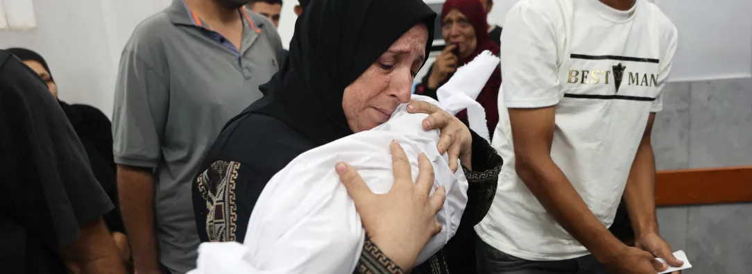 Ahmad llora mientras lleva el cuerpo envuelto en una manta de su hijo de seis meses, Yahya Sayyam, quien murió en un bombardeoisraelí.