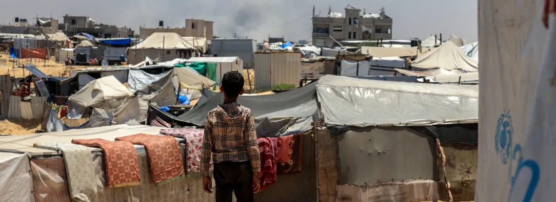 Un niño palestino observa cómo el humo se eleva a lo lejos durante el bombardeo israelí en Rafah.