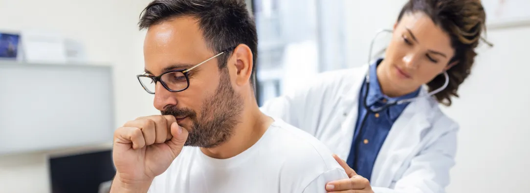 Señor tosiendo muy duro mientras la doctora lo examina