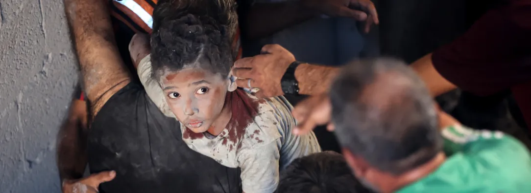 Palestinos transportan a un niño herido en el lugar donde se produjo un ataque israelí que destruyó varios edificios en el barrio de Al-Rimal, en la ciudad de Gaza.