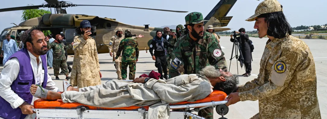 Voluntarios afganos y personal de seguridad talibán transportan a una víctima del terremoto evacuada por un helicóptero militar desde el distrito de Nurgal, en la provincia de Kunar, tras su llegada a Jalalabad para recibir asistencia médica.