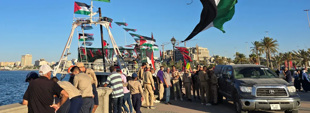 Personas posan para una foto frente al barco Omar al-Mukhtar, un barco libio que zarpó el 17 de septiembre para unirse a la Flotilla Global Sumud, en el puerto de Trípoli. 