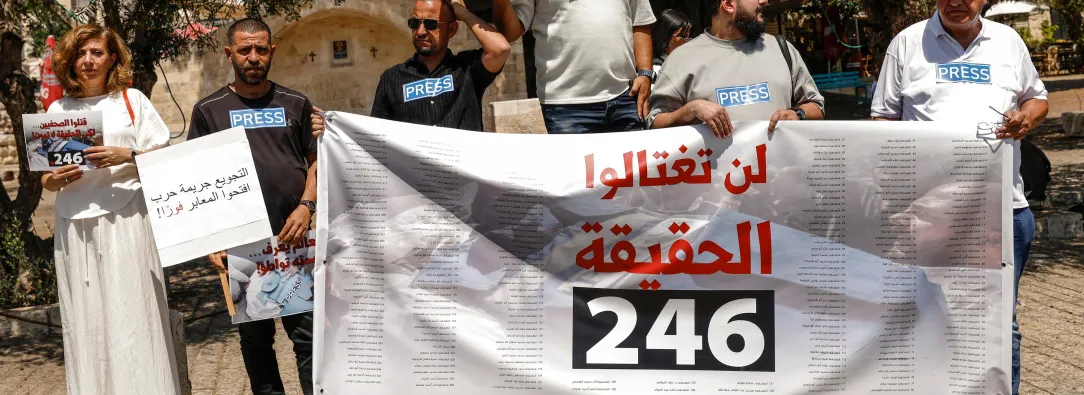 Periodistas árabe-israelíes levantan pancartas y una bandera palestina durante una manifestación en solidaridad con sus compañeros de profesión fallecidos en los ataques israelíes en la Franja de Gaza, en la ciudad norteña de Nazaret, el