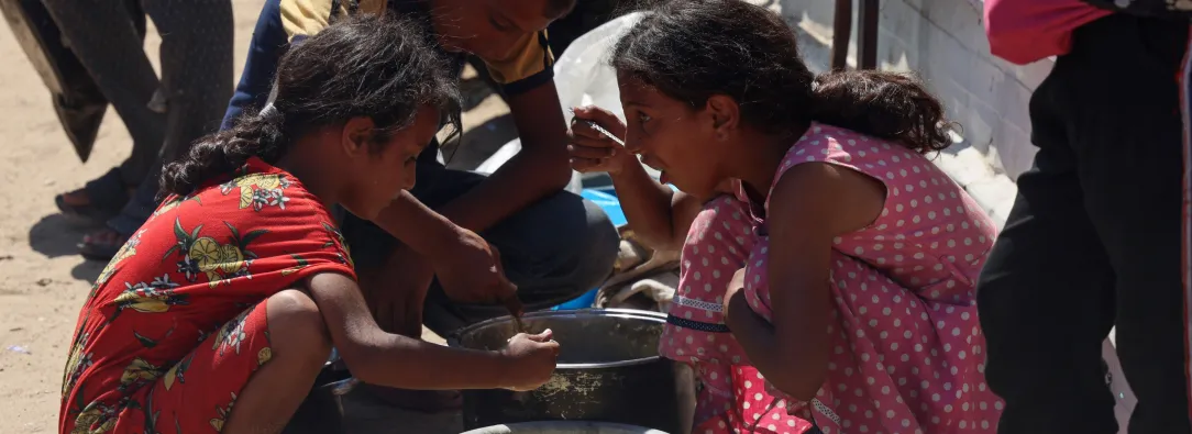 En un comedor social de Jan Yunis, en el sur de la Franja de Gaza, se reparten raciones de comida caliente entre los niños palestinos. Mientras esperan su turno, algunos comen arroz cocido.