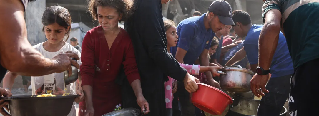 Los palestinos desplazados de Gaza se reúnen para recibir raciones de comida frente a la mezquita Imam al Shafi'i, dañada, donde se han refugiado familias, en el barrio de Zeitoun de la ciudad de Gaza.