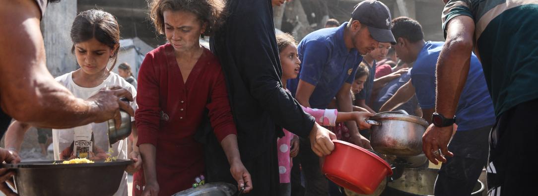 Los palestinos desplazados de Gaza se reúnen para recibir raciones de comida frente a la mezquita Imam al Shafi'i, dañada, donde se han refugiado familias, en el barrio de Zeitoun de la ciudad de Gaza.