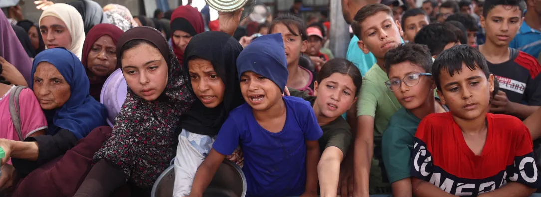 Niños palestinos se reúnen para recibir raciones de comida de un comedor benéfico en Nuseirat, en la Franja de Gaza central.