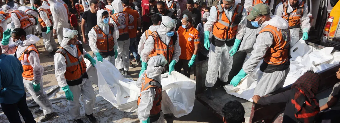 Miembros de Defensa Civil descargan bolsas con los restos mortales de los miembros de la familia Shahebar, que fueron enterrados en tumbas temporales, mientras son trasladados al cementerio Sheikh Shaaban, en la ciudad de Gaza, el 24 de octubre.