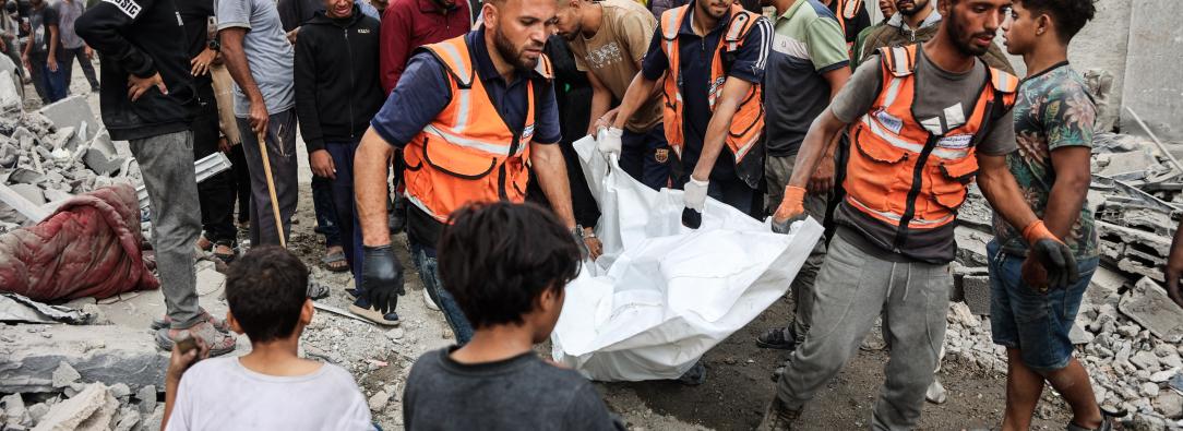 Palestinos transportan un cadáver que recuperaron de los escombros de una casa destruida en un ataque israelí perpetrado durante la noche en la ciudad de Gaza.