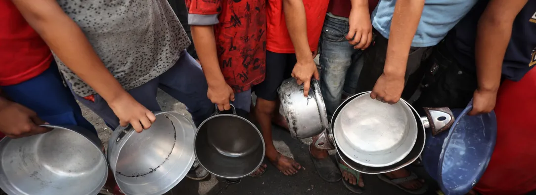 Niños palestinos hacen cola frente a un comedor social en el campo de refugiados de Nuseirat, en el centro de la Franja de Gaza. 