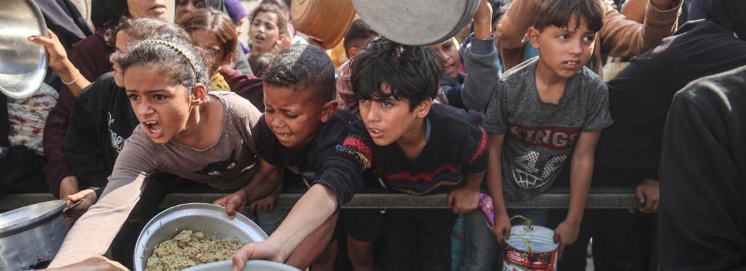Jóvenes palestinos desplazados esperan con sus recipientes para recibir una ración de comida en el campo de refugiados de Nuseirat, en el centro de la Franja de Gaza, tras hambruna declarada por la ONU en el enclave. 