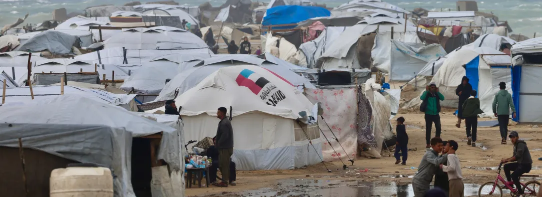 Los desplazados palestinos caminan cerca de tiendas de campaña y refugios improvisados mientras la región sufre las frías condiciones invernales en el campo de refugiados de Al-Mawasi, en el sur de la Franja de Gaza. 