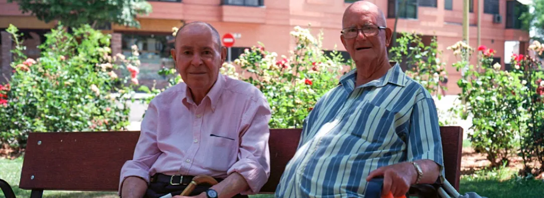 dos adultos mayores sentados en una banca de parque