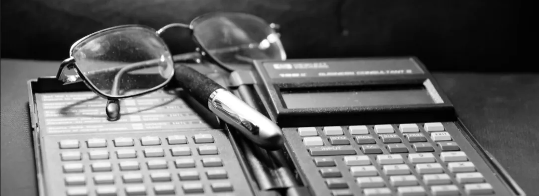 calculadora financiera antigua, gafas y lapicero