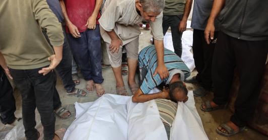 Un palestino llora sobre los cuerpos cubiertos con sábanas de sus familiares, muertos en un ataque israelí contra una panadería improvisada instalada en una tienda de campaña en la calle Al-Nassr, en la ciudad de Gaza.