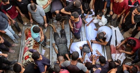 La gente rodea los cadáveres de palestinos, algunos muertos en los ataques israelíes de madrugada y otros asesinados el día anterior mientras buscaban ayuda humanitaria cerca de Zikim, al oeste de Beit Lahia, en el patio del hospital al-Shifa de la ciudad de Gaza.