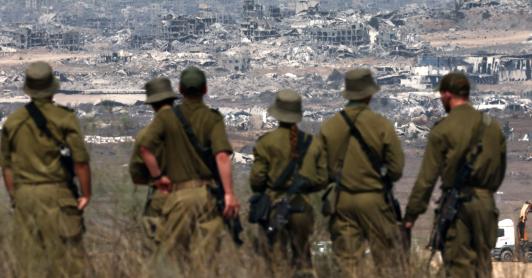 Soldados del ejército israelí observan los edificios destruidos en la Franja de Gaza mientras se encuentran en la frontera con el territorio palestino.