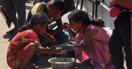 En un comedor social de Jan Yunis, en el sur de la Franja de Gaza, se reparten raciones de comida caliente entre los niños palestinos. Mientras esperan su turno, algunos comen arroz cocido.