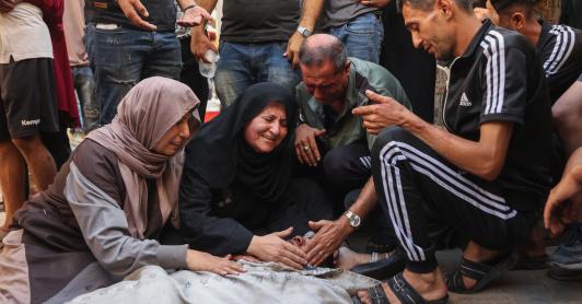 Los palestinos lloran junto al cadáver de un familiar asesinado en los ataques israelíes contra la ciudad de Gaza al amanecer, en el hospital Al-Shifa. 