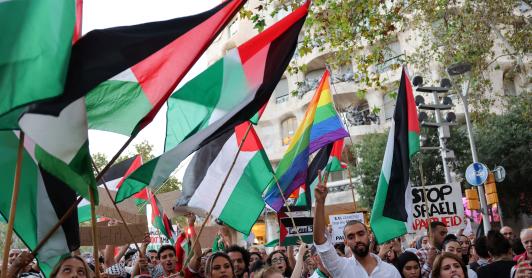 Manifestantes hacen gestos y ondean banderas palestinas durante una concentración convocada por la «Comunitat Palestina de Catalunya» (Comunidad Palestina de Cataluña) en solidaridad con los palestinos, frente al edificio «Casa Milà» del arquitecto español Antonio Gaudí, conocido popularmente como «La Pedrera», en Barcelona.
