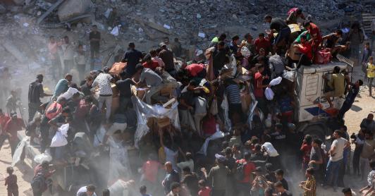 Los palestinos se apresuran a recibir paquetes de alimentos después de que los camiones de ayuda entraran por el paso fronterizo de Karem Abu Salem, en Jan Yunis, al sur de la Franja de Gaza.