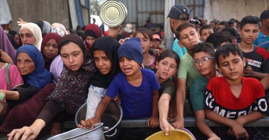 Niños palestinos se reúnen para recibir raciones de comida de un comedor benéfico en Nuseirat, en la Franja de Gaza central.